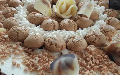 Torta decorata con biscotti, panna montata, cioccolato bianco a forma di rosa e granella. Il re del gelato trama, un capolavoro da gustare.