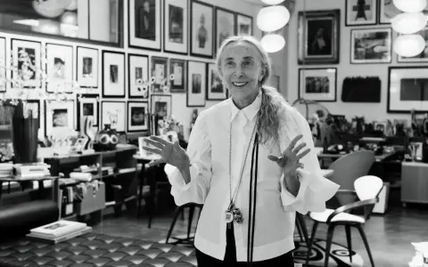Donna elegante con camicia bianca, un'icona di stile che incarna la moda di Milano. Le sue mani aperte raccontano storie di creatività e design.