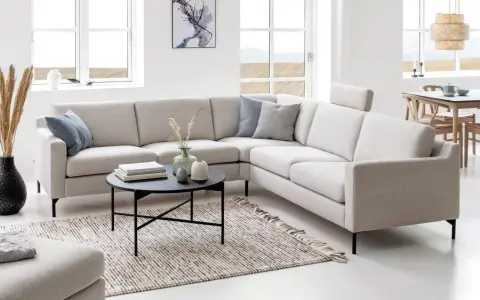 Inspiration kuddar till grå soffa: en ljusgrå hörsoffa med blå och grå mönstrade kuddar, ett runt svart soffbord med böcker och vaser, samt en randig matta.