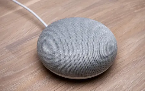 En grå Google Home Mini på ett trägolv, redo att styra ditt smarta hem med Verisure.