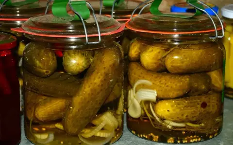 Słoiki pełne chrupiących ogórków po kaszubsku, z dodatkiem cebuli i przypraw, gotowe na zimę.