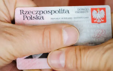 Dłonie trzymają polski dowód osobisty. Widoczny jest numer dowodu osobistego.