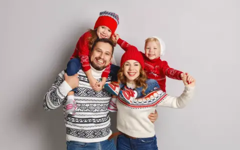 Famiglia felice con maglioni natalizi coordinati, un'ottima ispirazione per idee outfit natale.