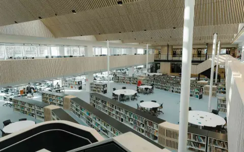 Storslagen biblioteksmiljö med bokhyllor, läsplatser och en modern arkitektur. Här kan man hitta aaltos recensioner bland tusentals böcker.