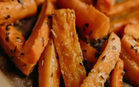 Carote in padella, tagliate a bastoncino e condite con erbe aromatiche, pronte per essere gustate.