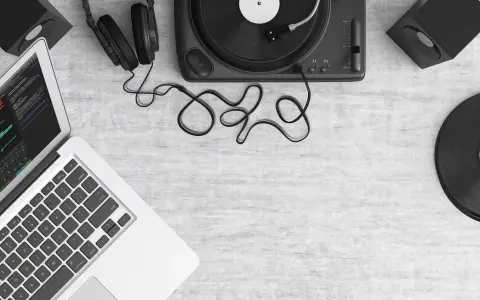 Laptop z programem do produkcji muzyki, gramofon, słuchawki i głośniki. Tworzenie utworu muzycznego z samplera.