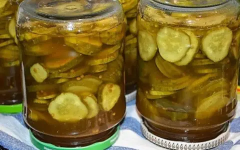 Słoiki pełne plasterków ogórków w zalewie z przyprawami, gotowe do podania jako dodatek do dań. Te ogórki w curry to smak lata zamknięty w słoiku.