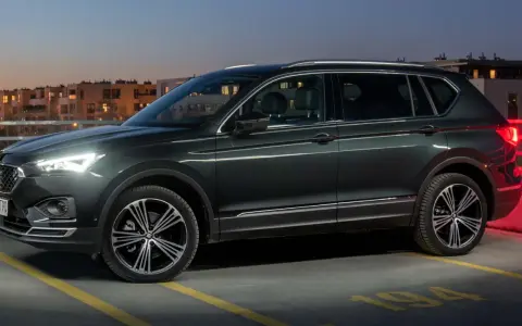 Ciemnozielony SUV, jeden z najbardziej polecanych samochodów 7-osobowych, zaparkowany na dachu parkingu nocą.