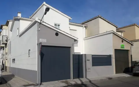 Fachada de casa con garaje, lista para como pintar una pared exterior en mal estado.