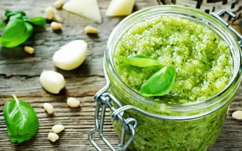 Frisches Pesto machen: Basilikum, Pinienkerne, Knoblauch und Parmesan auf rustikalem Holz.