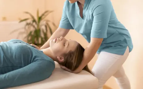 Fizjoterapeuta delikatnie masuje mięsień obojczykowo sutkowy pacjentki, przynosząc ulgę.