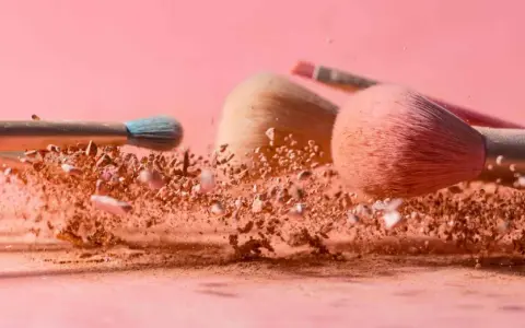 Pudry do makijażu w chmurze pyłu, pędzle do aplikacji pudru setting.