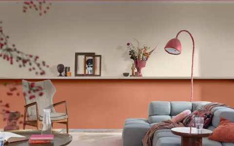 Soggiorno con pareti bicolore: la parte inferiore è color terracotta, quella superiore color crema. Arredamento moderno con divano grigio e poltrona.