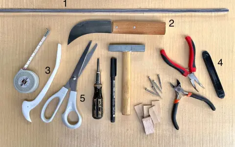 Outils pour le **matériel vitrail** : ruban à mesurer, ciseaux, couteau, marteau, pinces, clous et petits morceaux de bois.