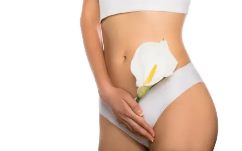 Kobieta w białej bieliźnie trzyma białą kalę. Efekt labioplastyki laserowej przed i po.