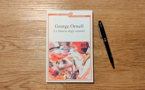 Copertina del libro "La fattoria degli animali" di George Orwell, con una penna nera appoggiata accanto.