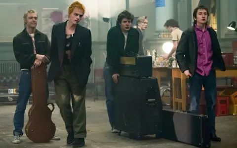 Les membres des Sex Pistols se tiennent prêts pour un concert, guitare et amplis à portée de main.