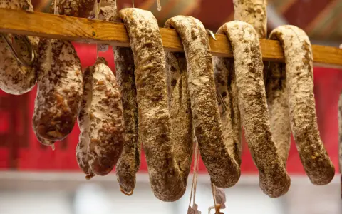 Saucissons secs, une spécialité culinaire auvergnate, pendent sur un support en bois.