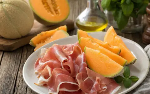 Piatto con fette di prosciutto e spicchi di melone, un classico antipasto italiano.