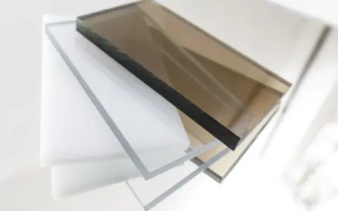 Stapel von transparenten und braunen Polycarbonatplatten. Die Kanten zeigen die Dicke und die Möglichkeit, Polycarbonat zu lackieren.