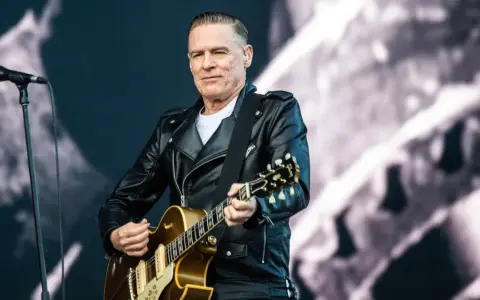 Bryan Adams w skórzanej kurtce gra na gitarze, przypominając piosenkę z Robin Hooda.
