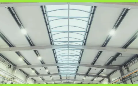 Interno di un capannone con luminose coperture industriali e lucernari curvi che illuminano lo spazio.