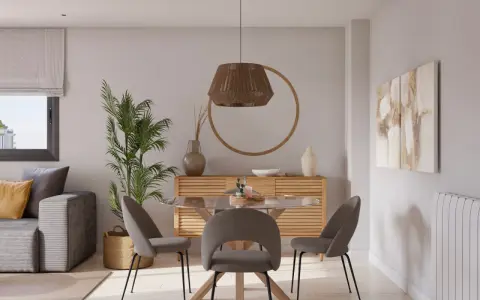 Acogedor salon comedor muy pequeño con sofá gris, mesa redonda de cristal y sillas tapizadas. Decoración natural con planta y cesta.