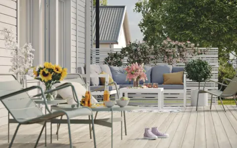 En härlig altan runt huset med bekväma möbler, solrosor och en inbjudande atmosfär för avkoppling.