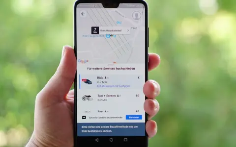 Hand hält Smartphone mit der besten Taxi App Deutschlands. Anzeige zeigt Fahrtoptionen nach Köln Hauptbahnhof.