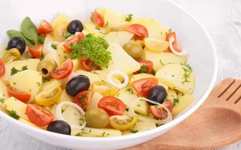 Insalata di patate pugliese con pomodorini, olive nere e verdi, cipolla e prezzemolo fresco. Un piatto estivo e saporito.