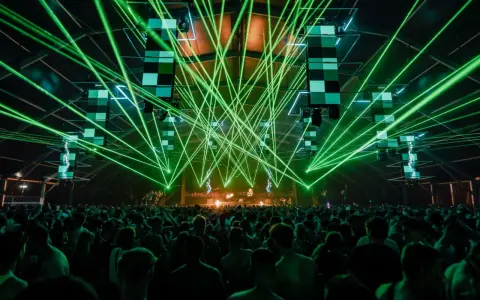 Tłum ludzi na koncercie, zielone lasery tworzą niesamowitą atmosferę. To właśnie jest **rave co to** za przeżycie!