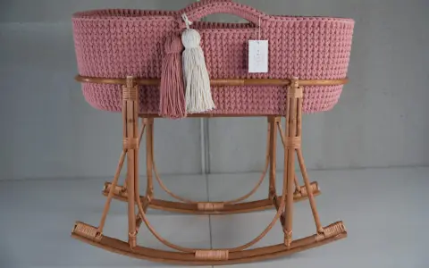 Moisés crochet rosa con borlas y base de mimbre. Un lugar acogedor para el bebé.