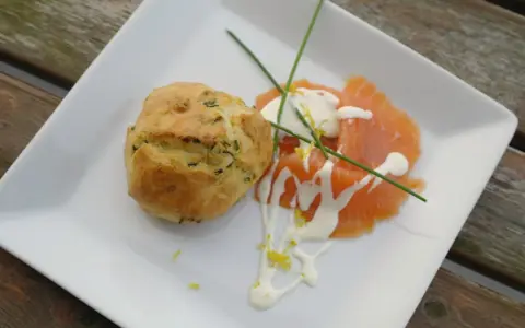 Matiga muffins med örter serveras med gravad lax, en klick gräddfil och citronzest.