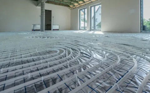 Rozłożone rury do ogrzewania podłogowego wodnego w nowym domu. Instalacja gotowa do zalania wylewką.