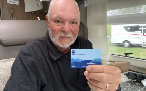Man håller upp ett kort med texten "autopassferje.no", redo för resor mellan Norge och Sverige.