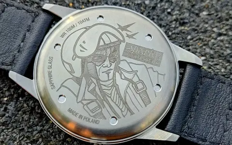 Napis na deklu zegarka: "MADE IN POLAND", WR 100M/10ATM, SAPPHIRE GLASS. Grawer przedstawia pilota w hełmie i goglach.