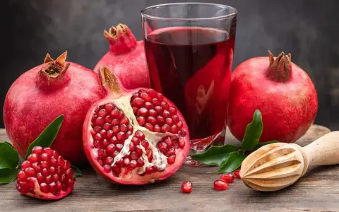 Frische Granatäpfel und Saft auf einem Holztisch. Ein gesunder Genuss, besonders in der Schwangerschaft.
