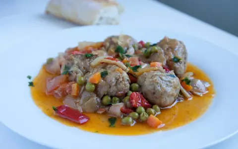 Albondigas a la jardinera, jugosas y sabrosas, con guisantes, zanahoria y pimiento rojo en una salsa dorada.