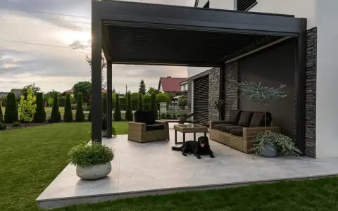 Nowoczesna pergola z zacienieniem, meble wypoczynkowe i pies. Idealne miejsce do relaksu, zastanawiasz się, czym zabezpieczyć pergole?