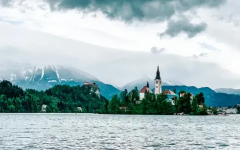 Jezioro Bled ze słynną wyspą i kościołem to obowiązkowy punkt, co warto zobaczyć w Słowenii. W tle góry.