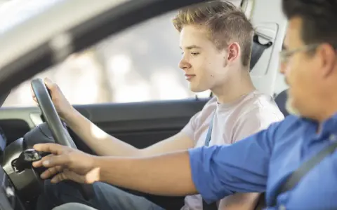 Młody kierowca uczy się jeździć, a instruktor czuwa. Zastanawiam się, ile godzin jazdy na kat. B jeszcze przed nim.