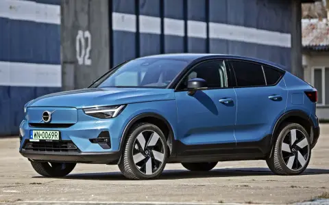 Niebieskie Volvo C40, elektryczny SUV coupe, parkuje przed budynkiem z numerem "02".