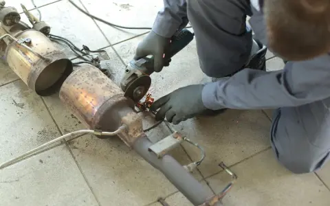 Meccanico con smerigliatrice effettua la rimozione fap da un pezzo di scarico auto, scintille volano.