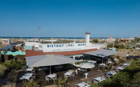 Il Bistrot del Mare a Rimini, con tavoli all'aperto e vista sulla spiaggia affollata, offre specialità romagnole.