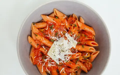 Penne w sosie pomidorowym z ziołami i parmezanem. Idealny przepis na zdrowy makaron, który zachwyci smakiem.