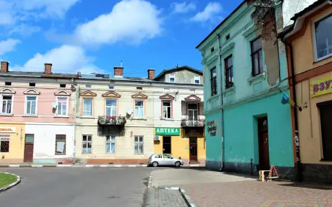 Kolorowe kamienice przy ulicy, gdzie mój stryj kiedyś mieszkał. Srebrny samochód zaparkowany obok apteki.