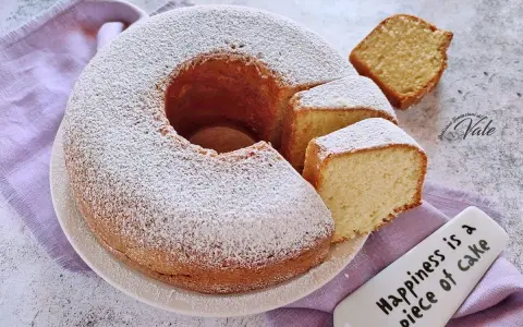 Un ciambellone soffice come una nuvola, cosparso di zucchero a velo, con fette tagliate pronte da gustare.