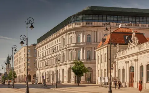 Elegancka kamienica z nowoczesnym dachem, być może najdroższy hotel w Polsce, przy słonecznej ulicy z zabytkowymi latarniami.