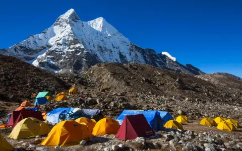 Obóz pod majestatycznym szczytem Karakorum. Kolorowe namioty rozstawione na kamienistym zboczu, gotowe na przyjęcie alpinistów.