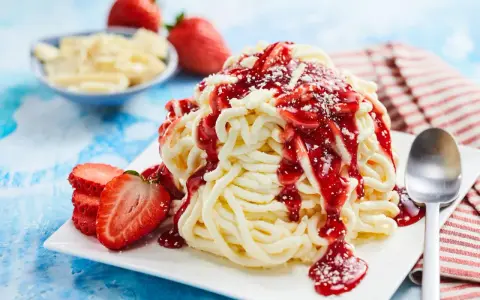 Ein köstliches Spaghetti-Eis-Dessert mit Erdbeersoße und frischen Erdbeeren, bereit zum Genießen.